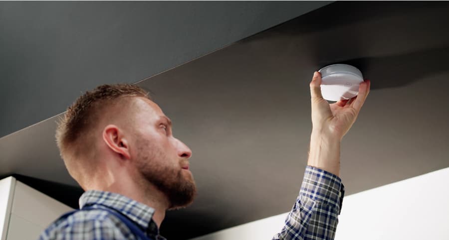 Man connecting a smoke detector inside a home